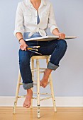 Woman with canvas & paintbrushes sitting on stool