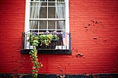 Rote Hausfassade mit Fenster, Blumenkasten & amerikanischer Flagge