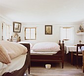 Bäuerliches Schlafzimmer mit Nachttopf unter dem Federbett und Heiligenbildern an der Wand
