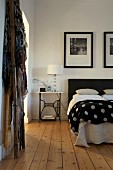 Double bed with black and white polka dot bedspread in rustic bedroom