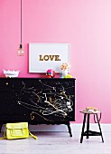 Ornaments on cabinet splattered with paint, yellow bag, telephone on stool, picture on wall and pendant lamp