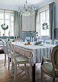 Dining area with rustic wooden table, chandelier and linen tablecloth