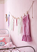 Children's clothes hung on string in pink room