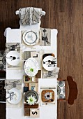 Top view of artistically set table - place settings with various motifs on plates and white table cloth
