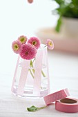 Glass jar with decorative masking tapes, pink daisies inside