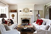 White sofas and coffee table in front of open fireplace in traditional, elegant country house