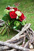 Bouquet with red roses on wreath of branches