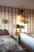 Schlafzimmer mit Wandverkleidung mit 3D-Effekt und freistehender Badewanne
