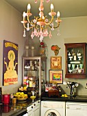 Corner of kitchen with antique crockery in display cabinets above worksurface; chandelier with pink crystal ornaments in foreground