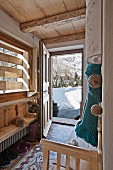 Open front door in foyer of wooden chalet with view of snowy landscape