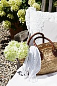 White cushions and raffia bag on deckchair in front of country house