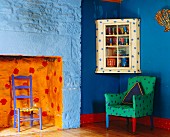 Polstersessel in bunt bemalten eklektischen Zimmer mit blauen Wänden und orangefarbener Kaminnische
