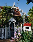 Kleines Landhaus mit Bauerngarten, weißem Zaun & Rosenspalier