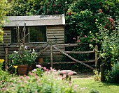 Gartenhütte aus Holz mit rustikalem Zaun