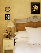 Französisches Doppelbett mit geflochtenem Kopfteil & Nachttisch in Schlafzimmer mit gepunkteter Tapete