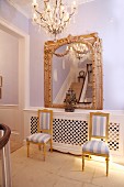 Stühle mit vergoldetem Holzrahmen vor gerahmten Spiegel im Rokoko-Stil an fliederfarbener Wand im Treppenraum