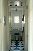 Blick durch offene Tür auf Toilette mit Schachbrettmusterboden in traditionellem Ambiente