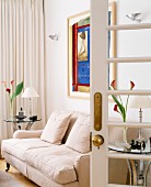Blick in Wohnzimmer mit beiger Couch & Beistelltischchen aus Glas