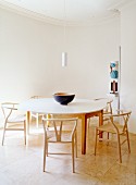 Schlichter Essraum mit runden Wänden, rundem Esstisch & Holzstühlen