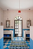 Blue and white chequered floor in bathroom with arched door flanked by twin washstands