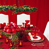 Weihnachtlich gedeckter Tisch und weiße Polsterstühle vor rotem Vorhang