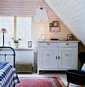Vintage cabinet painted white and metal bed in attic bedroom