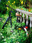 Vintage Fahrrad in blühendem Garten an vergrautes Holzgeländer gelehnt