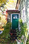 Green wooden house with small porch in autumnal garden