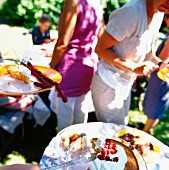 Leute essen Kuchen bei einem Gartenfest