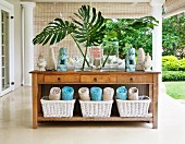 Spa oasis - rolled towels in baskets below rustic wooden console table on veranda of colonial-style villa