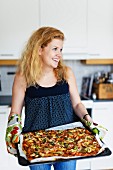 Yong smiling woman with freshly made pizza