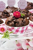 Chocolate muffins on glass cake stand decorated with flowers