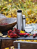 Rowan berries, thermos flasks & cups on table outdoors