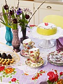 Table set with cake, pastries, flowers & floral cups and crockery