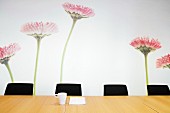 Blumen als Wandmalerei hinter unbesetztem Konferenztisch