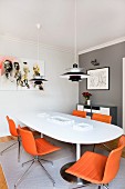 Poulsen pendant lamp above white dining table and swivel chairs with orange leather covers in corner with one grey wall
