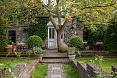 Idyllic cottage with terrace surrounded by garden and brick walls in vintage, artistic ambiance
