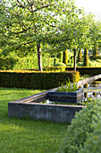 Well-tended landscaped gardens with geometric hedges, trees, lawns and concrete pool