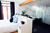 White bedroom with glass shower partition in open-plan bathroom