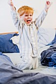 Little red-headed boy romping on parents' bed
