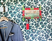 Key rack and suit jacket on coathanger on floral wallpaper