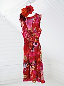 Floral, red dress hanging from pole in attic room