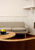 Couch with beige upholstery and round coffee table next to whitewashed brick wall