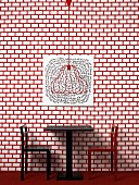 Tisch mit Stühlen vor rot-weiss gemusterter Wand