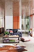 Elongated, open-plan living room with sofa, coffee table & animal skin rug