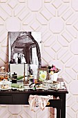 Cluttered dressing table with nostalgic black and white photo against pink, geometric wallpaper