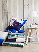Stacked blue and white cushions next to lamp on three-legged stool