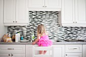 Girl standing on chair at kitchen counter