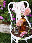 Flowers in vintage glass bottles on white chair