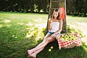 Adolescent girl sitting in orchard eating an apple